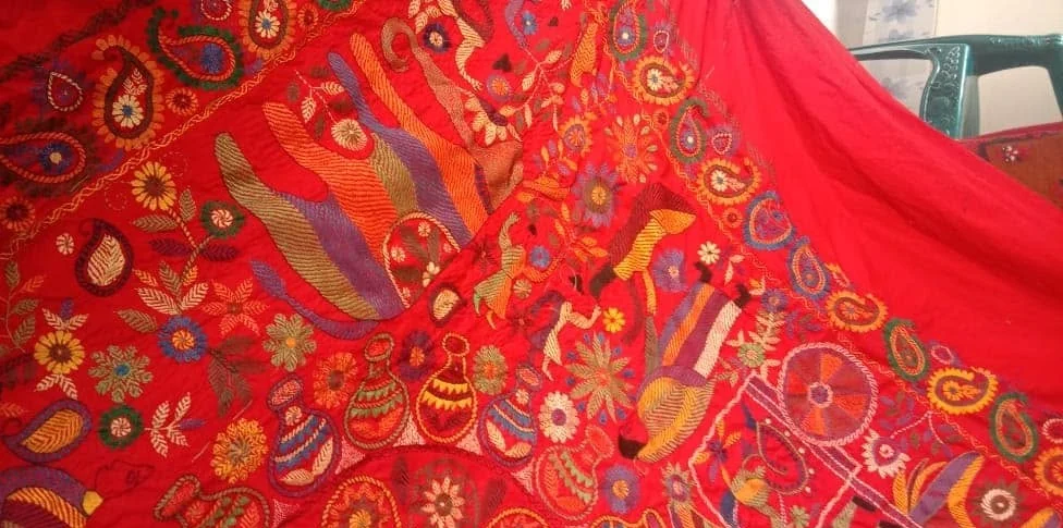 A hand-embroidered red kantha cloth gathered in loose folds