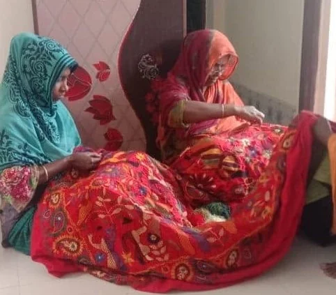 Two members going over a finished piece of kantha embroidery together