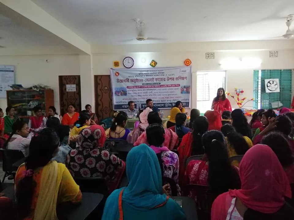 A speaker addressing seated trainees at the opening of a sewing training course