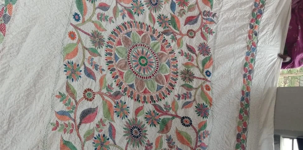 A finished nakshi kantha cloth hand-embroidered with a central medallion and flowering vines